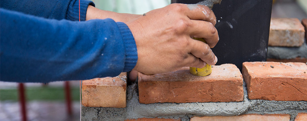 Tuckpointing and Masonry Repair - Man's hand tuckpointing bricks.