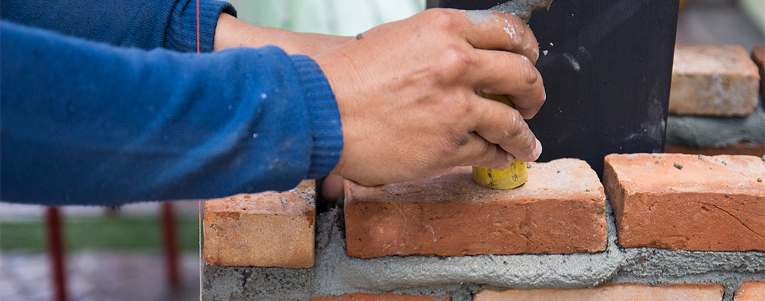 Traditions Chimney Sweeps original photo of tuckpointing and masonry repair. Tuckpointing and Masonry Repair - Man's hand tuckpointing bricks.